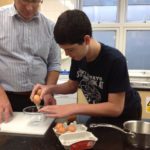 Student cracking eggs with a teacher in cooking class Student cracking eggs with a teacher in cooking class