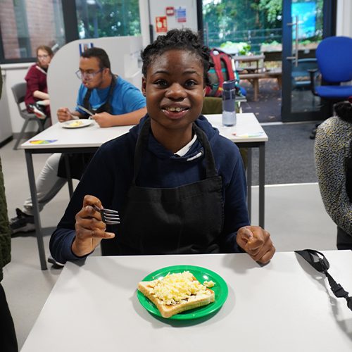 Eating a breakfast of scrambled eggs on toast that our student prepared herself.