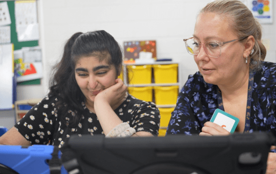 Student in Greenwich class supported by her teacher Student in Greenwich class supported by her teacher